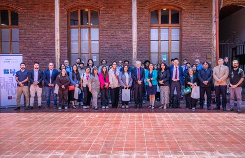 Un grupo de personas posando frente a un edificio de ladrillo en un evento formal.