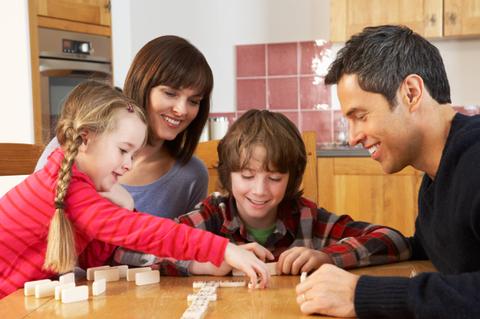 Una familia juega junta en la mesa, disfrutando de un momento divertido con fichas de dominó.