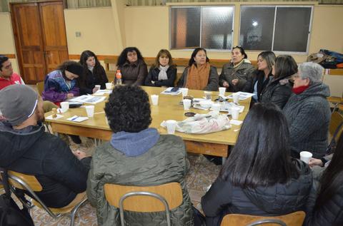 Un grupo de personas discutiendo alrededor de una mesa en un entorno interior.