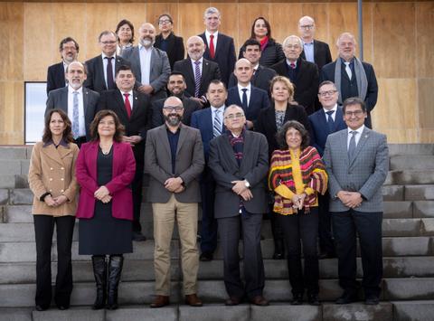 Un grupo de personas posando en una escalinata, vestidos de manera formal.