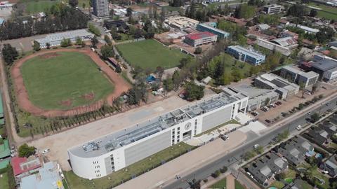 Una vista aérea de un complejo escolar con un campo deportivo y edificios cercanos.