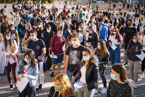 Un grupo numeroso de estudiantes con mascarillas se encuentra en un espacio al aire libre.