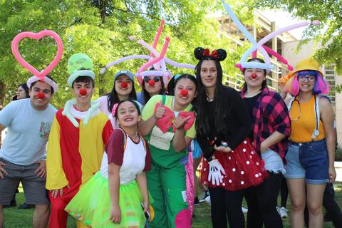 Un grupo de personas disfrazadas de payasos sonríe frente a la cámara en un ambiente festivo.