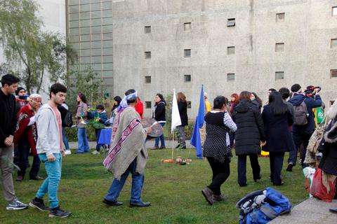 Un grupo de personas participa en un evento al aire libre, con banderas y actividades diversas en un entorno verde.