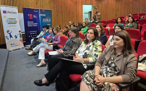 Un grupo de personas escucha atentamente en un evento educativo en Chile.