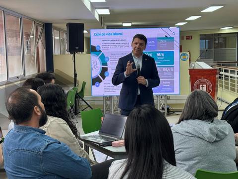Un expositor da una charla sobre el ciclo de vida laboral ante un grupo de personas.