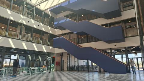Vista de un moderno edificio con escaleras y luz natural entrando por el techo.