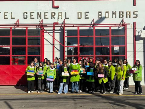Un grupo de personas con chaquetas verdes posando frente a un cuartel de bomberos en Chile.
