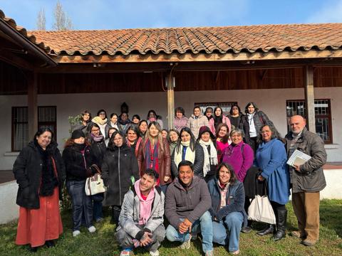 Un grupo grande de personas sonrientes posando en un evento al aire libre.
