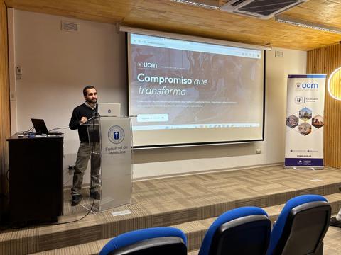 Un presentador en un auditorio muestra una página web sobre un compromiso transformador.