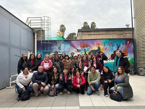 Un grupo de personas posando frente a un mural colorido en una actividad comunitaria.