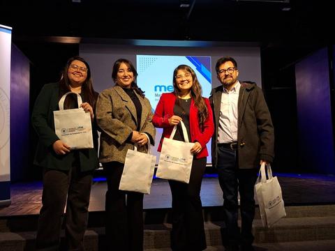 Un grupo de cuatro personas en un evento, sosteniendo bolsas y sonriendo.