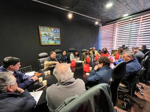 Reunión de trabajo en una sala con participantes alrededor de una mesa.