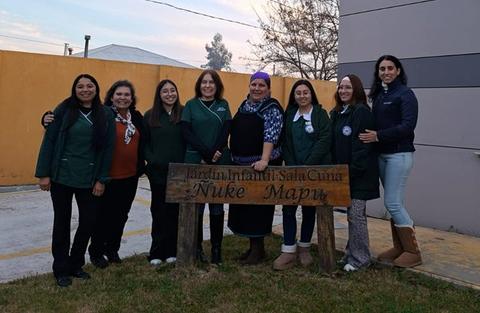 Un grupo de educadoras sonrientes posando frente a un jardín infantil llamado Nuke Mapu.