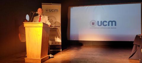 Un hombre de pie frente a un podio en un evento relacionado con la Universidad Complutense de Madrid.