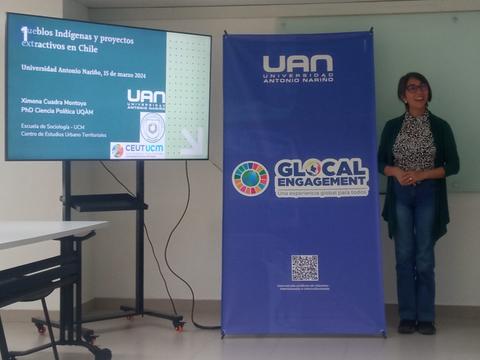 Una mujer presenta un proyecto sobre pueblos indígenas y proyectos extractivos en Chile en una universidad.