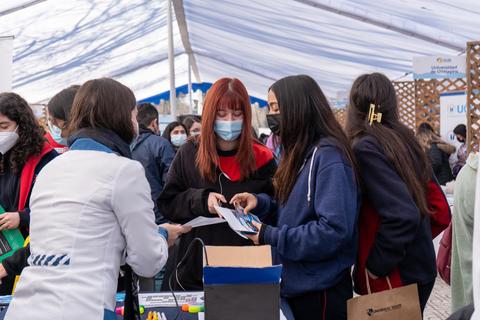Un grupo de jóvenes interactuando en un evento bajo una cubierta.