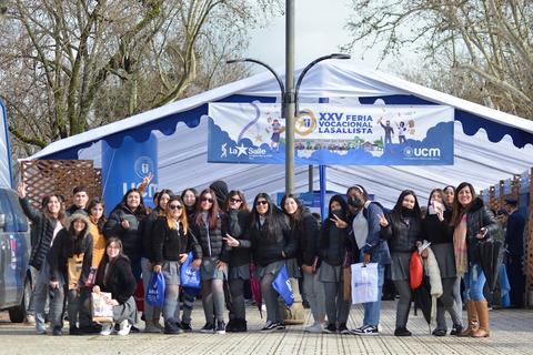 Un grupo de estudiantes sonríe frente a una carpa en una feria vocacional.