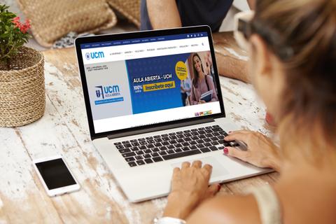 Una persona está usando una laptop mientras visualiza la página web de la UCM sobre inscripciones.