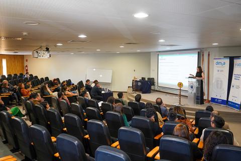Una presentación en un auditorio lleno de gente escuchando atentamente a la expositora.