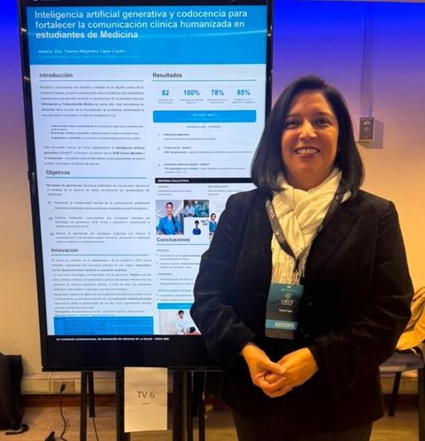 Una mujer sonriente posa frente a un cartel sobre inteligencia artificial en comunicación clínica para estudiantes de Medicina.