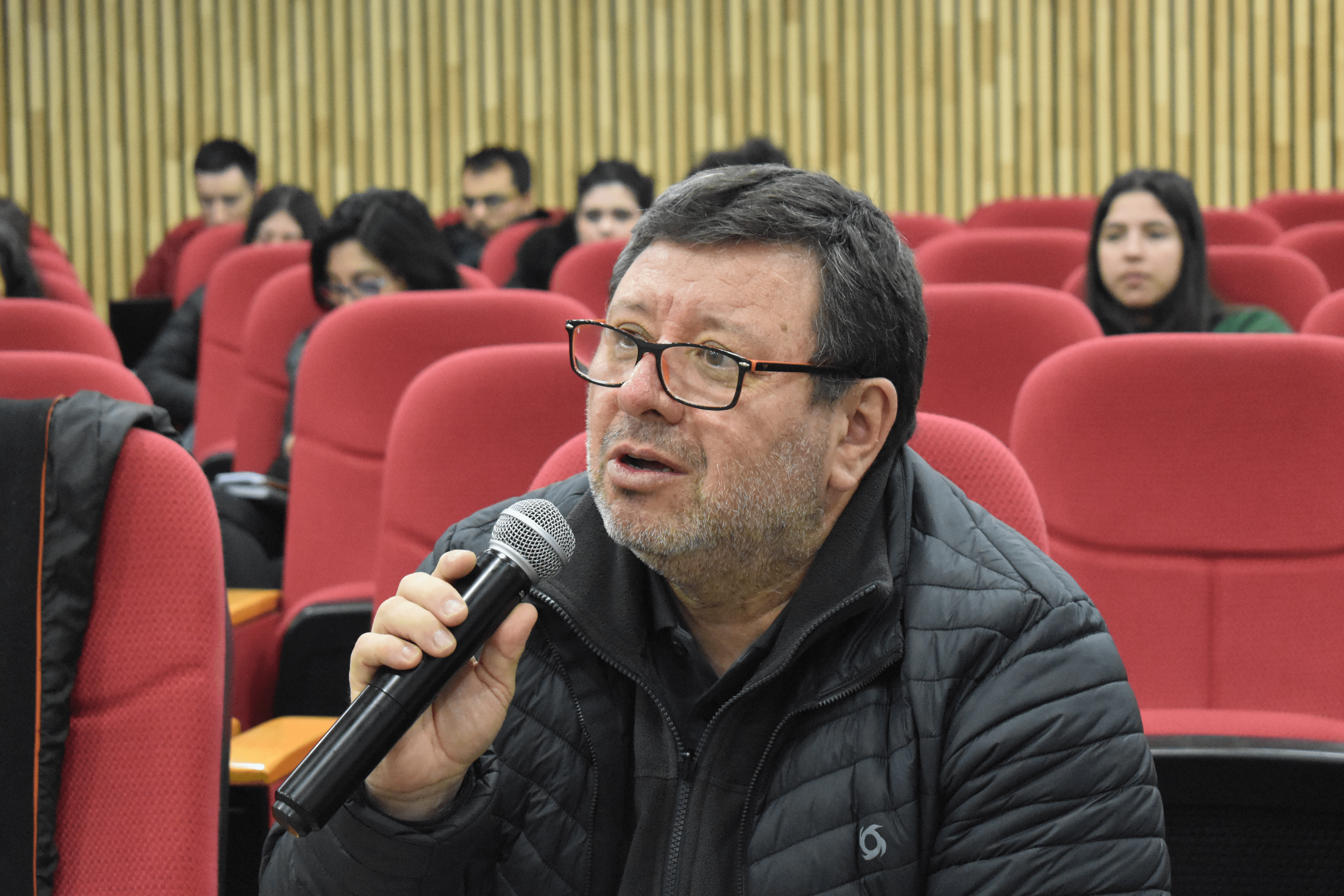 Un hombre comenta durante una charla en un auditorio lleno de gente.