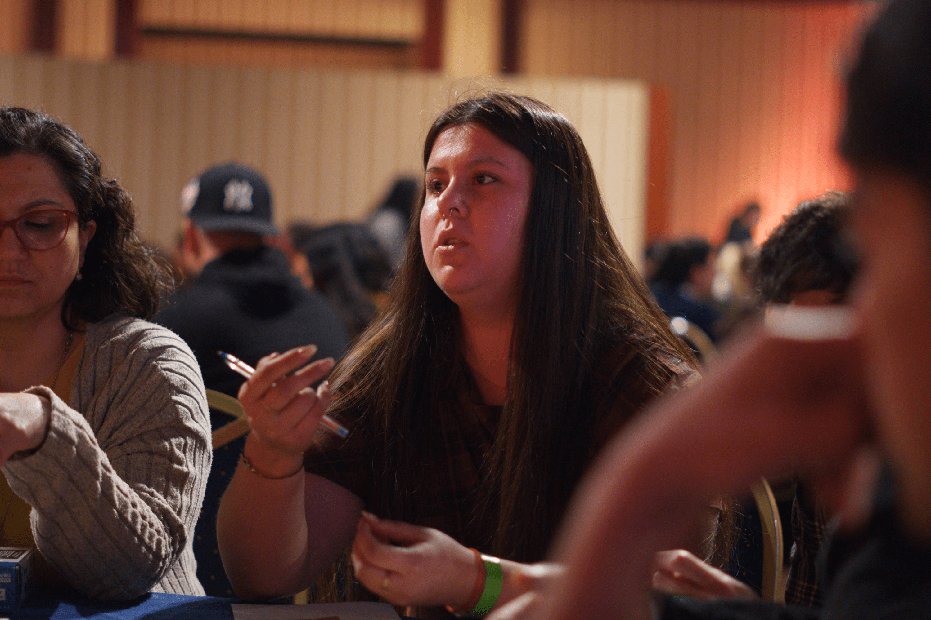 Una mujer conversa intensamente en un ambiente lleno de gente.