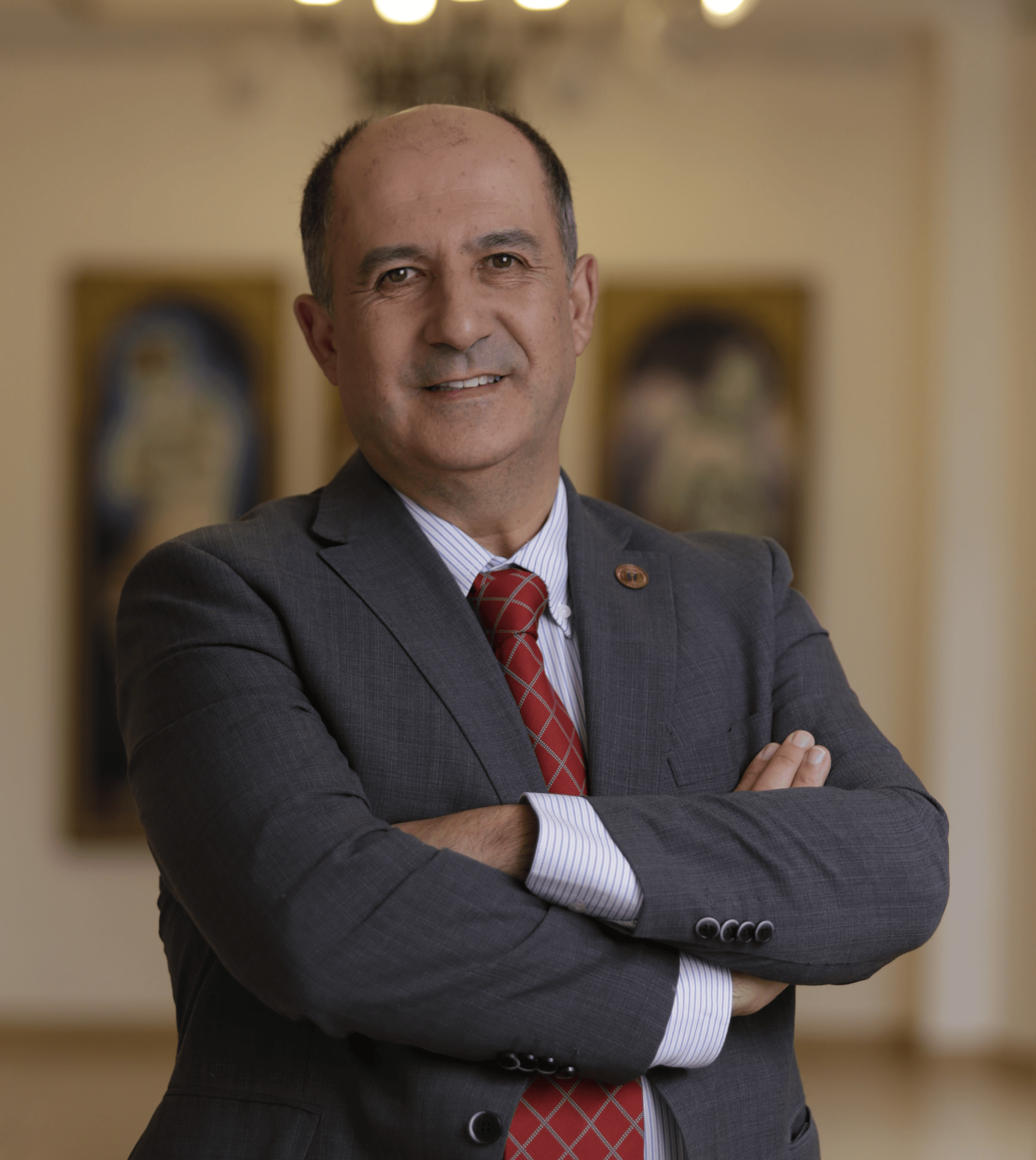 Un hombre sonriente en un ambiente elegante con cuadros al fondo.