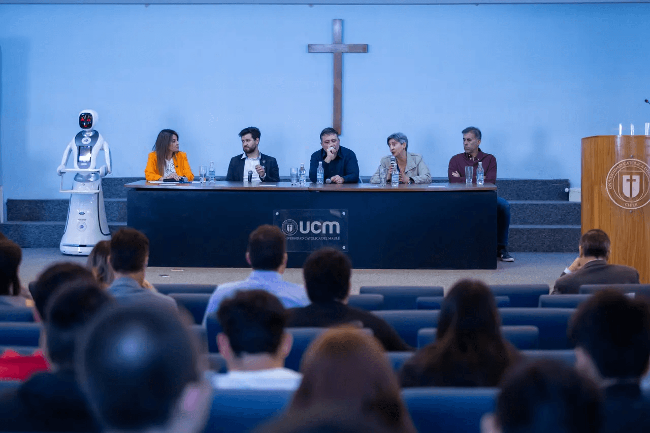 En un encuentro, un panel de expertos discute mientras un robot acompaña en la presentación.