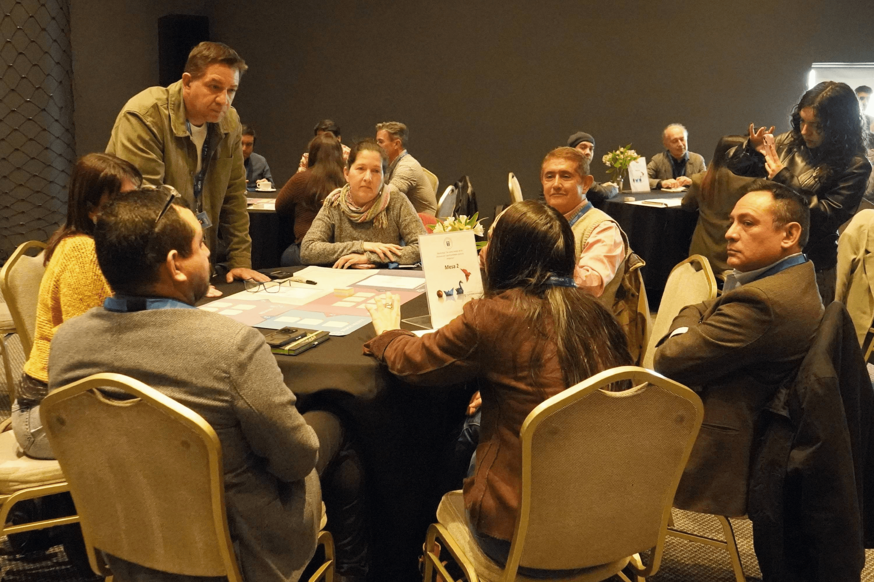 Un grupo de personas conversando y colaborando en una mesa durante un evento en Chile.