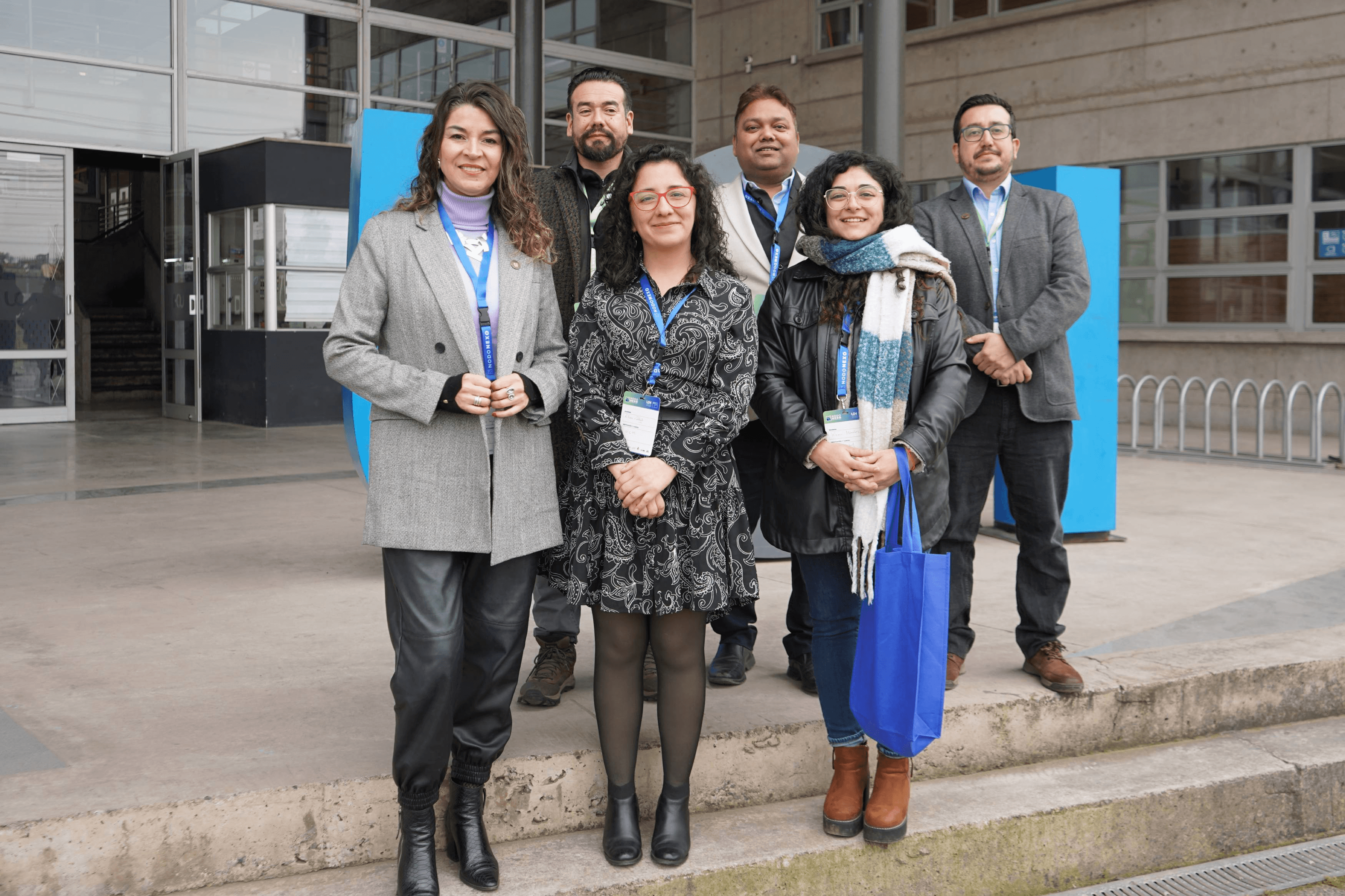 Un grupo de seis personas posando frente a un edificio en un ambiente profesional.