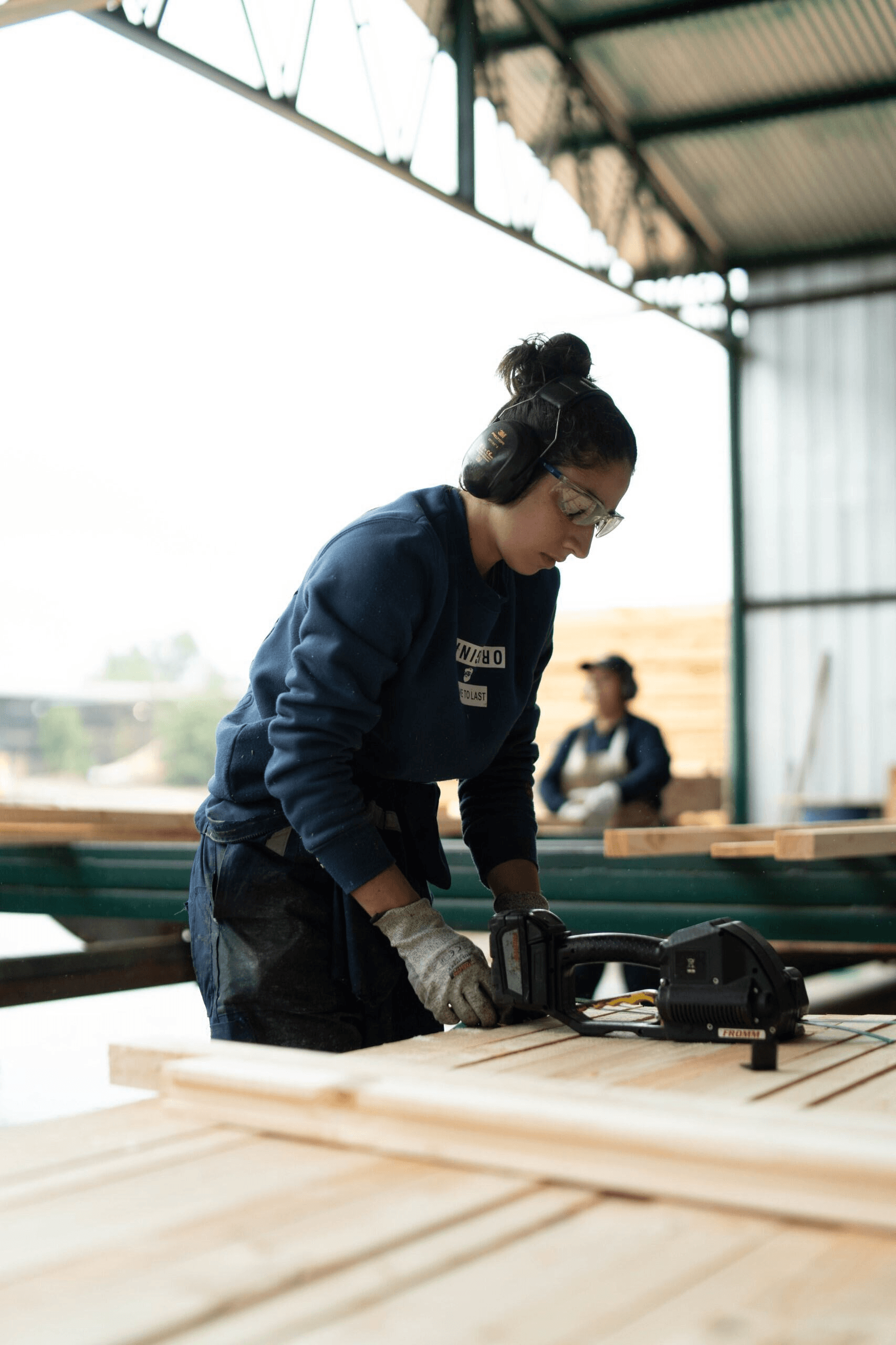 Una mujer trabajando en una carpintería, usando herramientas para dar forma a la madera.