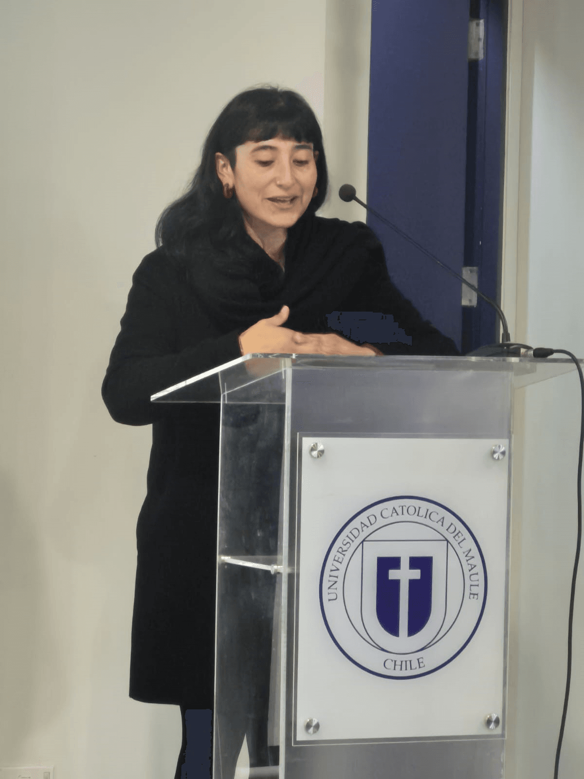Una mujer hablando en un podio en la Universidad Católica de Chile.