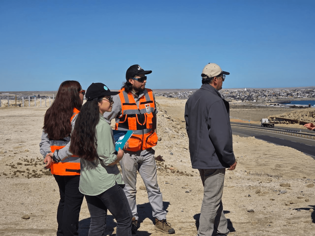 Un grupo de profesionales en terreno discutiendo un proyecto en una zona desértica.