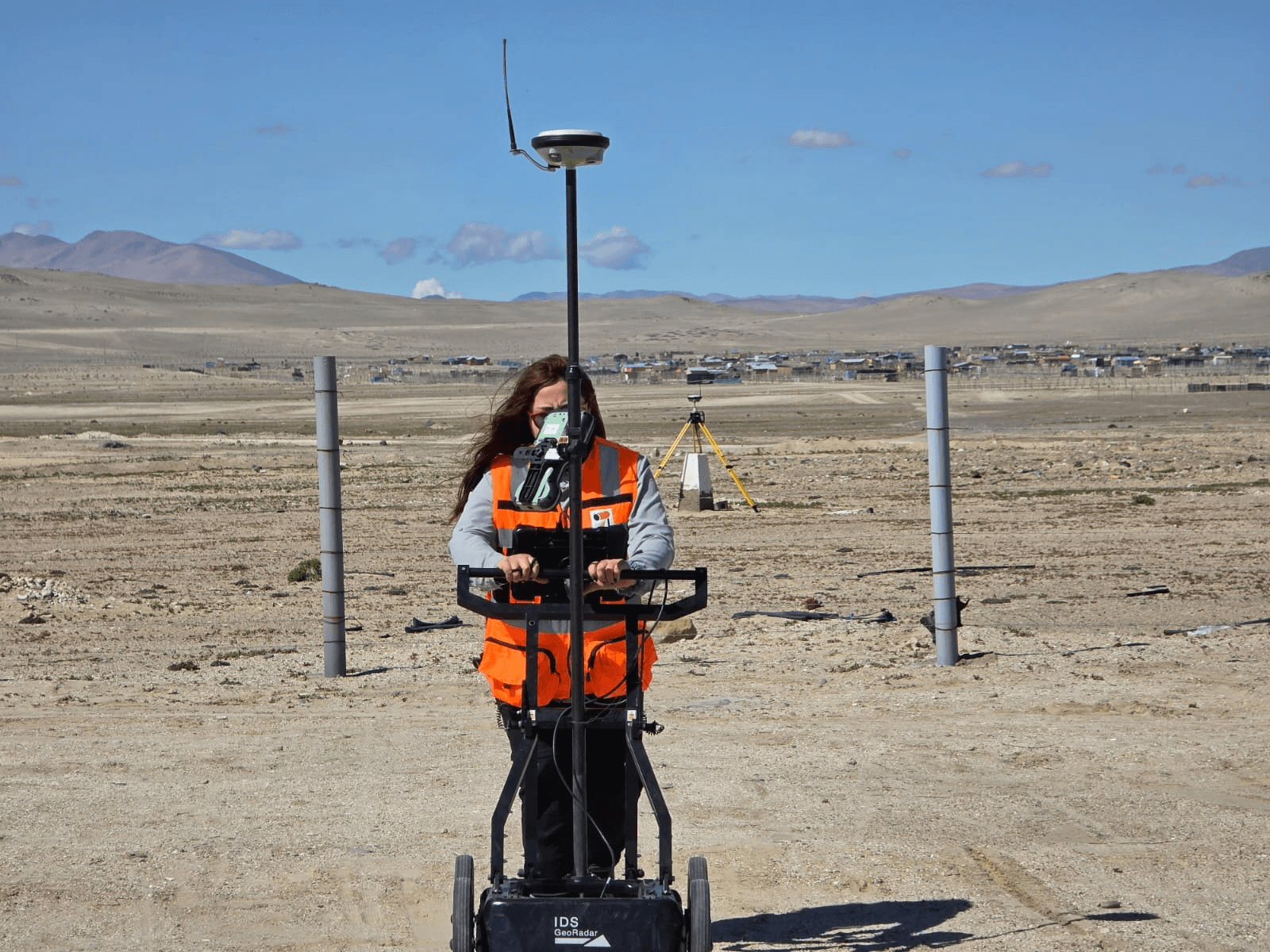 Una persona está realizando un trabajo de topografía en un terreno árido con un equipo especializado.